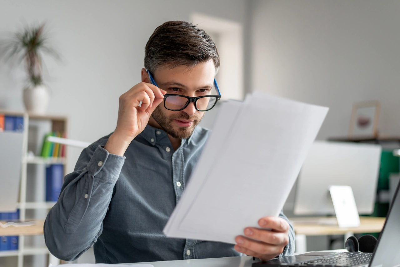 Uomo affari maturo preoccupato occhiali legge documenti ufficio controllo annuale